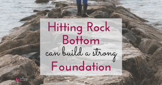 hitting rock bottom can build a strong foundation overlayed on image of rocks by the water