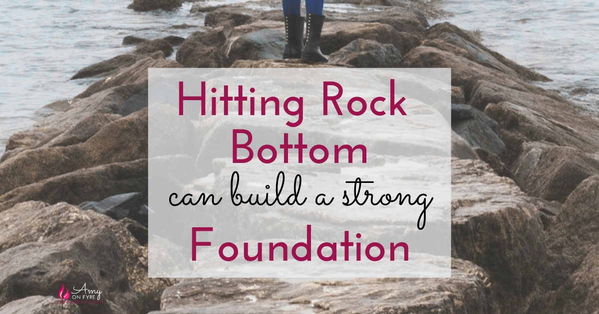 hitting rock bottom can build a strong foundation overlayed on image of rocks by the water